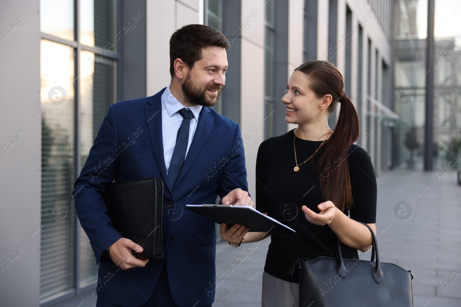 Happy coworkers discussing something near office building Photo of Happy coworkers discussing something near office building