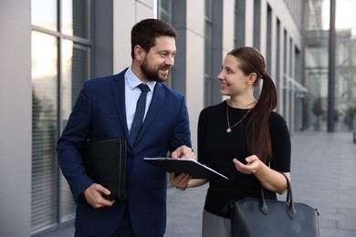 Photo of Happy coworkers discussing something near office building