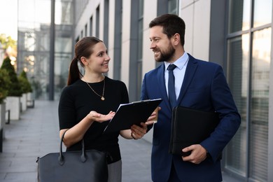Photo of Happy coworkers discussing something near office building