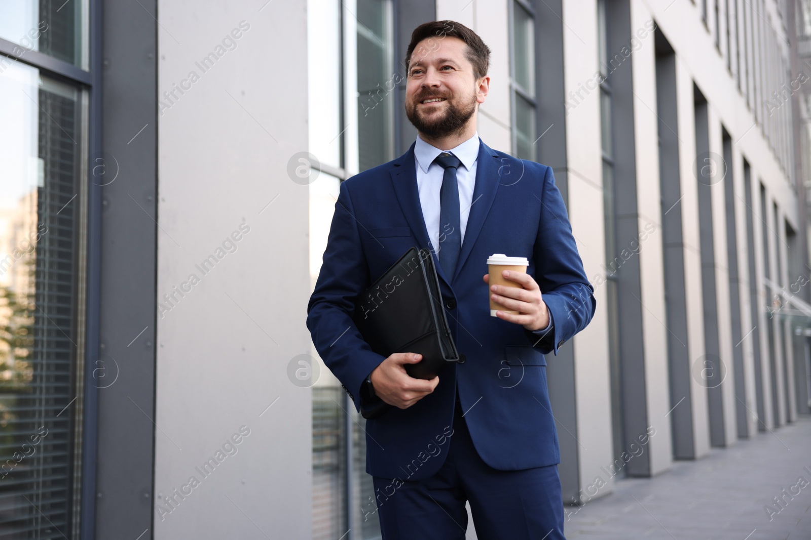 Successful businessman with coffee near office building Photo of Successful businessman with coffee near office building