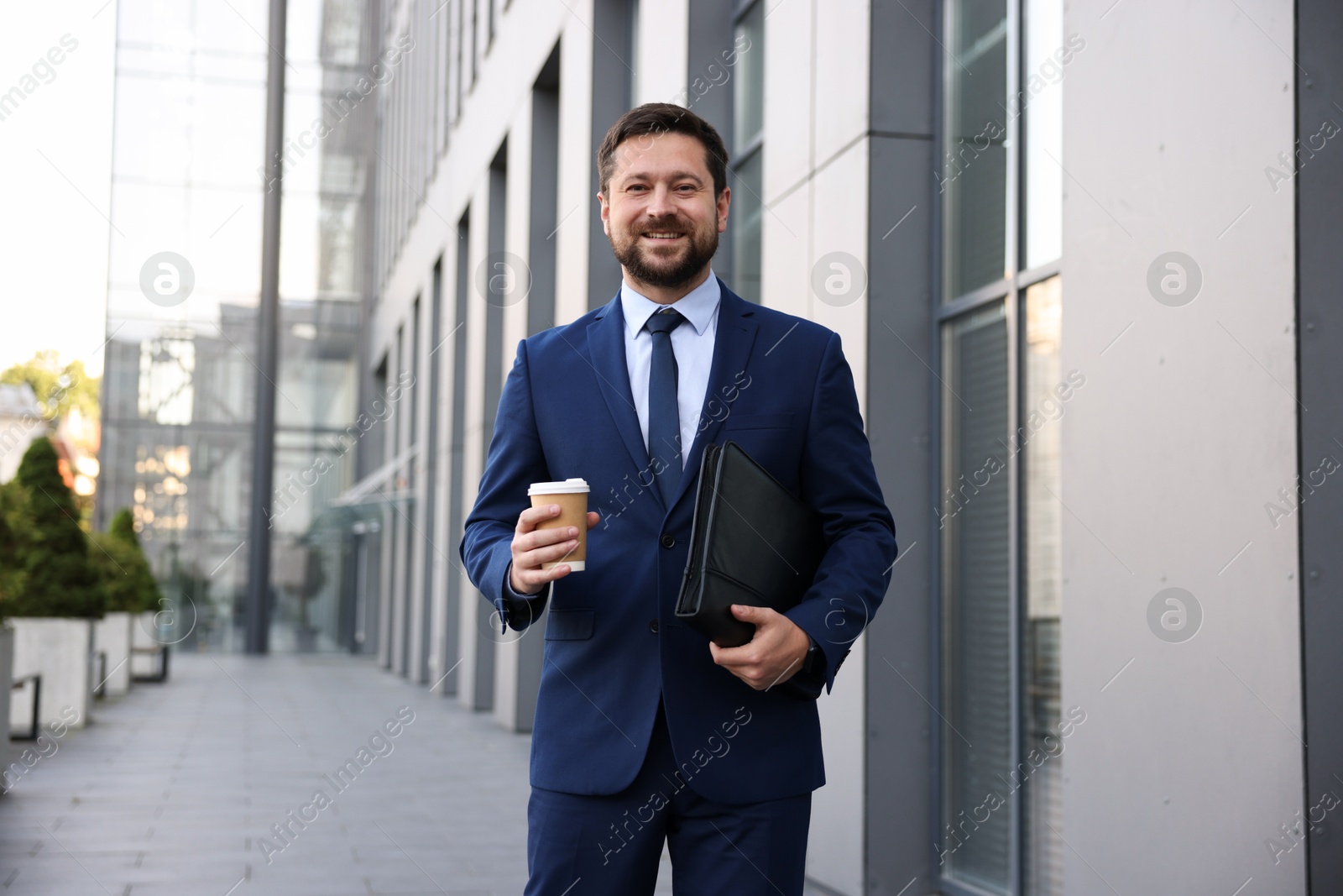 Photo of Successful businessman with coffee near office building