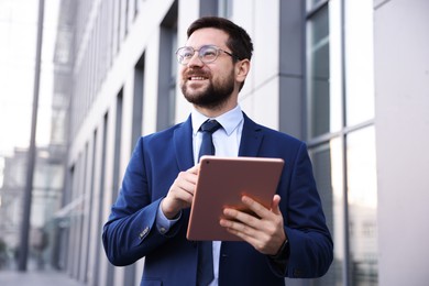 Photo of Successful businessman with tablet near office building