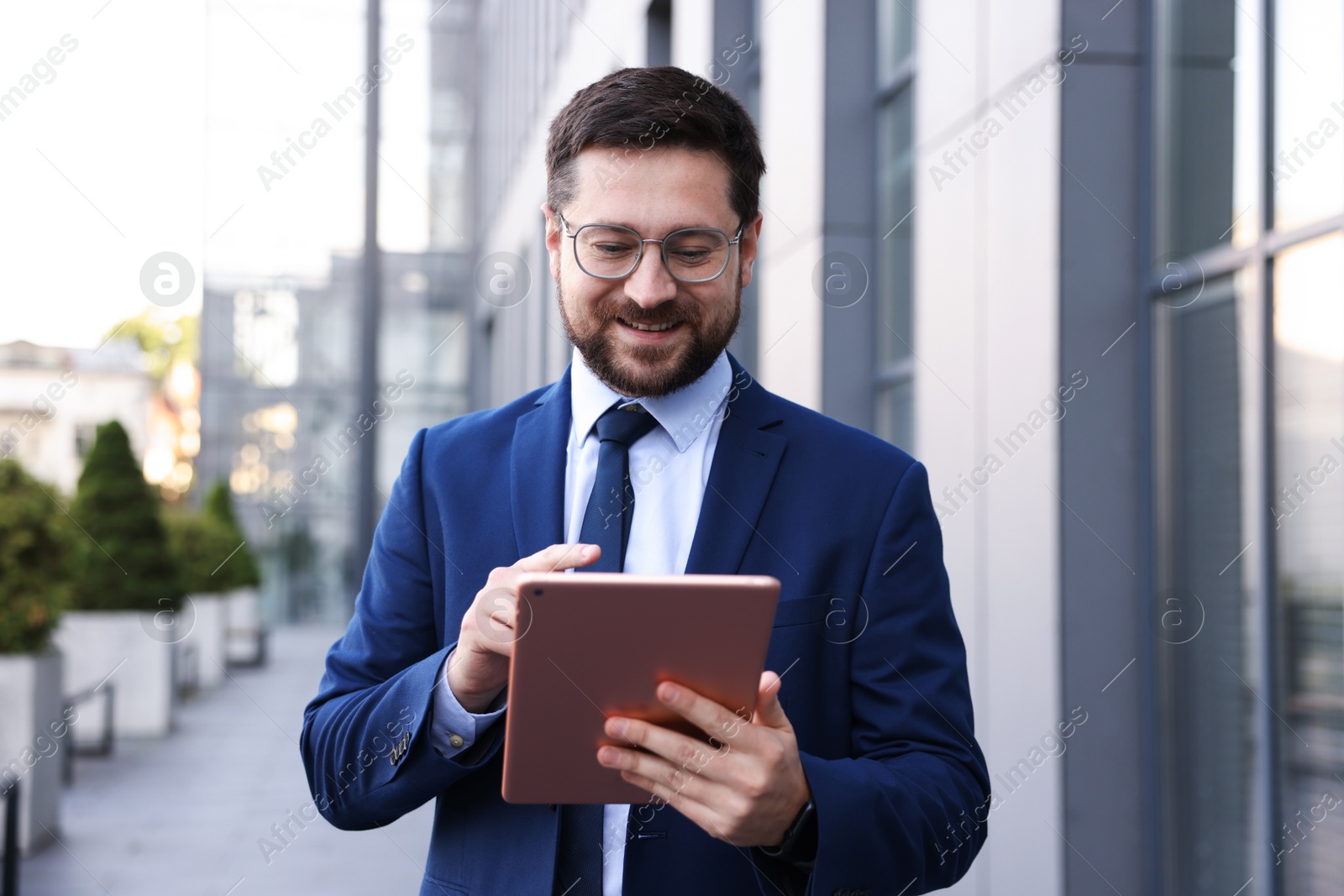 Successful businessman with tablet near office building Photo of Successful businessman with tablet near office building