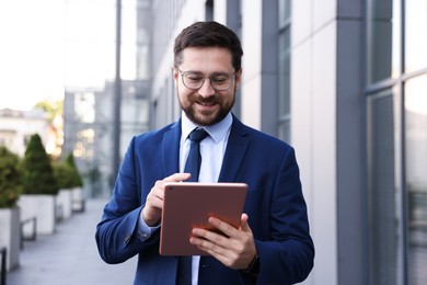 Photo of Successful businessman with tablet near office building