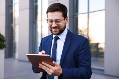 Photo of Successful businessman with tablet near office building