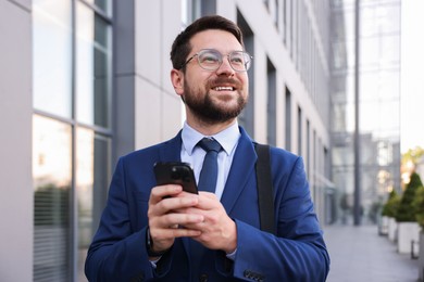 Photo of Successful businessman with smartphone near office building