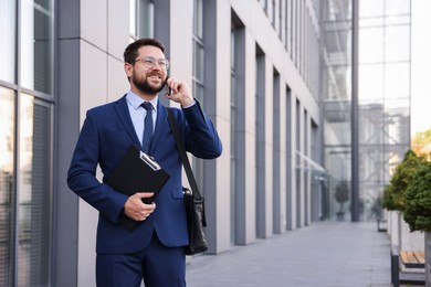 Photo of Successful businessman talking on phone near office building. Space for text