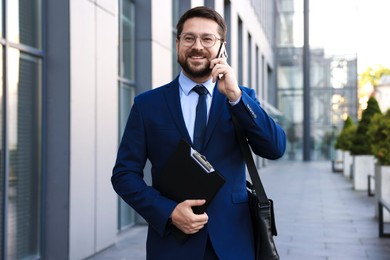 Photo of Successful businessman talking on phone near office building