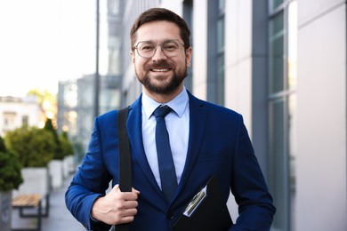 Photo of Successful businessman with clipboard near office building