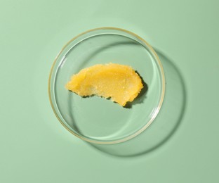 Photo of Cosmetic product in Petri dish on green background, top view