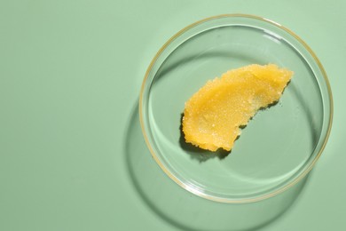 Photo of Cosmetic product in Petri dish on green background, top view. Space for text