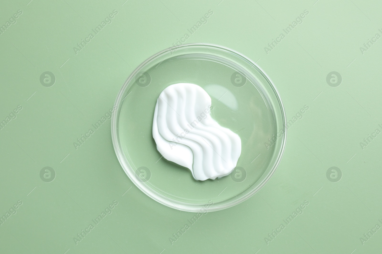 Cosmetic product in Petri dish on green background, top view Photo of Cosmetic product in Petri dish on green background, top view