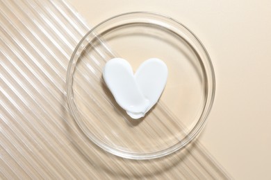 Photo of Cosmetic product in Petri dish on beige background, top view