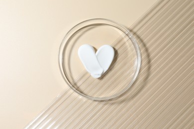 Photo of Cosmetic product in Petri dish on beige background, top view
