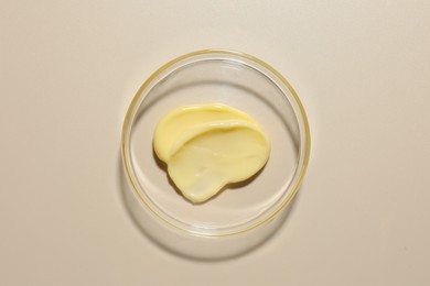 Photo of Cosmetic product in Petri dish on beige background, top view