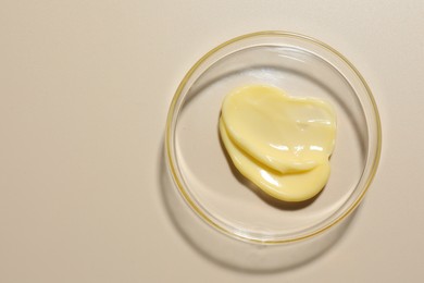 Photo of Cosmetic product in Petri dish on beige background, top view. Space for text