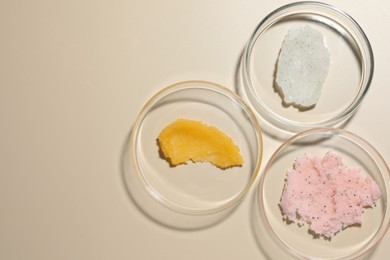 Photo of Different cosmetic products in Petri dishes on beige background, flat lay. Space for text