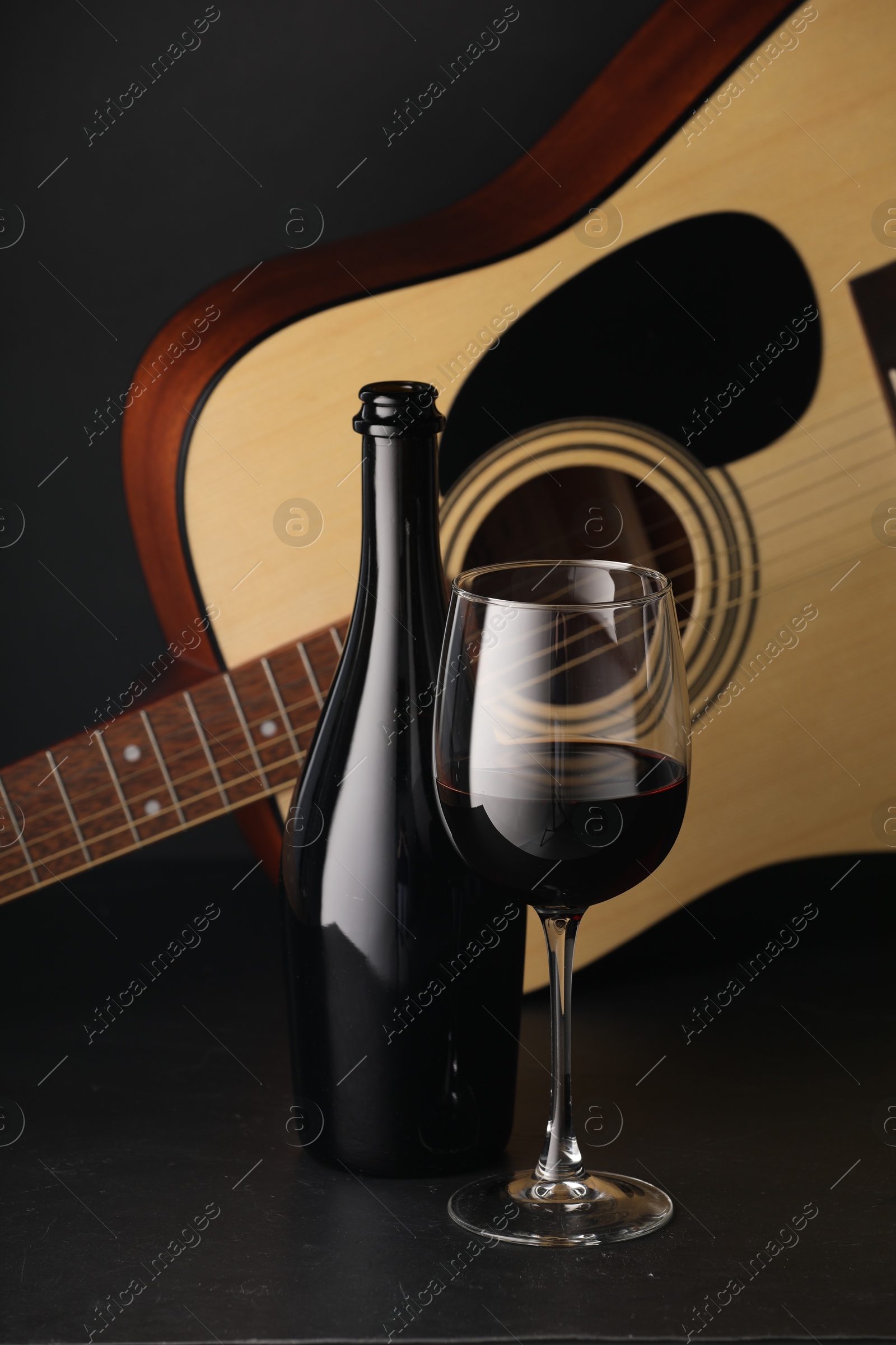 Acoustic guitar and red wine on black table, closeup Photo of Acoustic guitar and red wine on black table, closeup