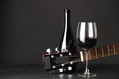 Photo of Acoustic guitar and red wine on black table, closeup. Space for text