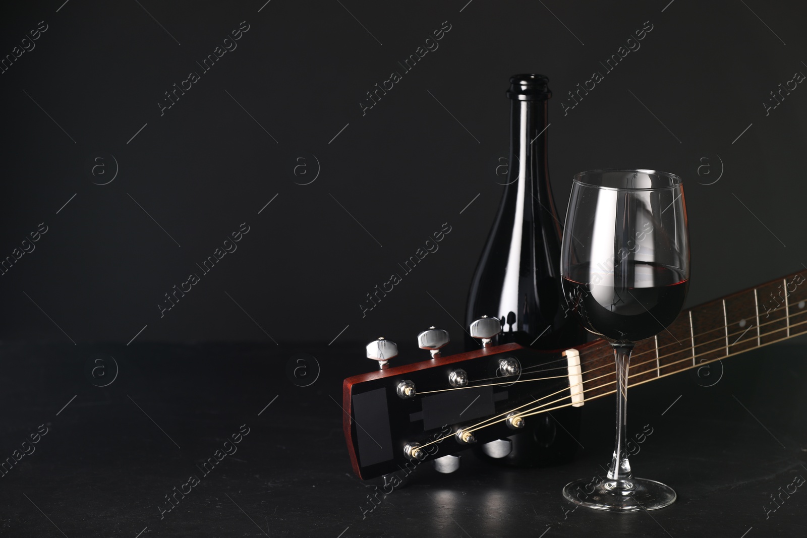 Acoustic guitar and red wine on black table, closeup. Space for text Photo of Acoustic guitar and red wine on black table, closeup. Space for text