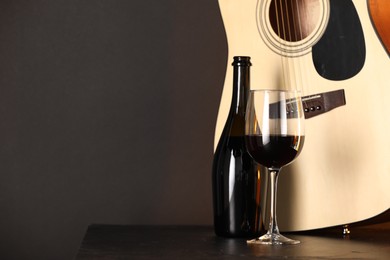 Photo of Acoustic guitar and red wine on black table, closeup. Space for text