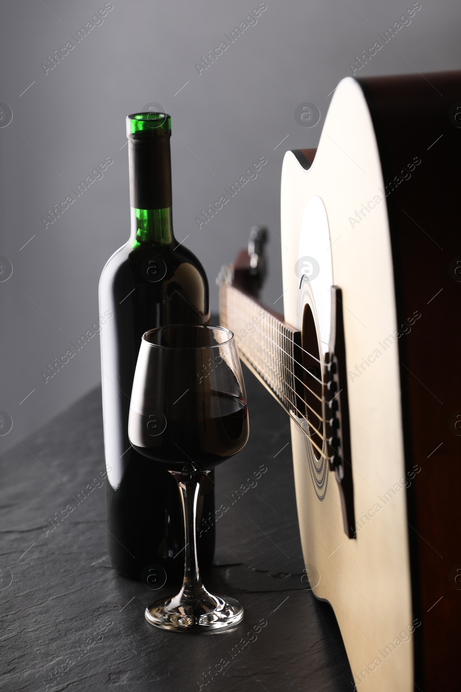 Acoustic guitar and red wine on black table, closeup Photo of Acoustic guitar and red wine on black table, closeup