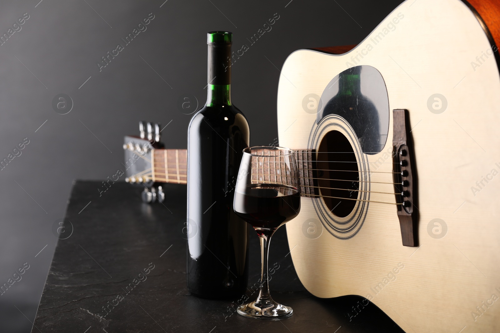 Acoustic guitar and red wine on black table, closeup Photo of Acoustic guitar and red wine on black table, closeup