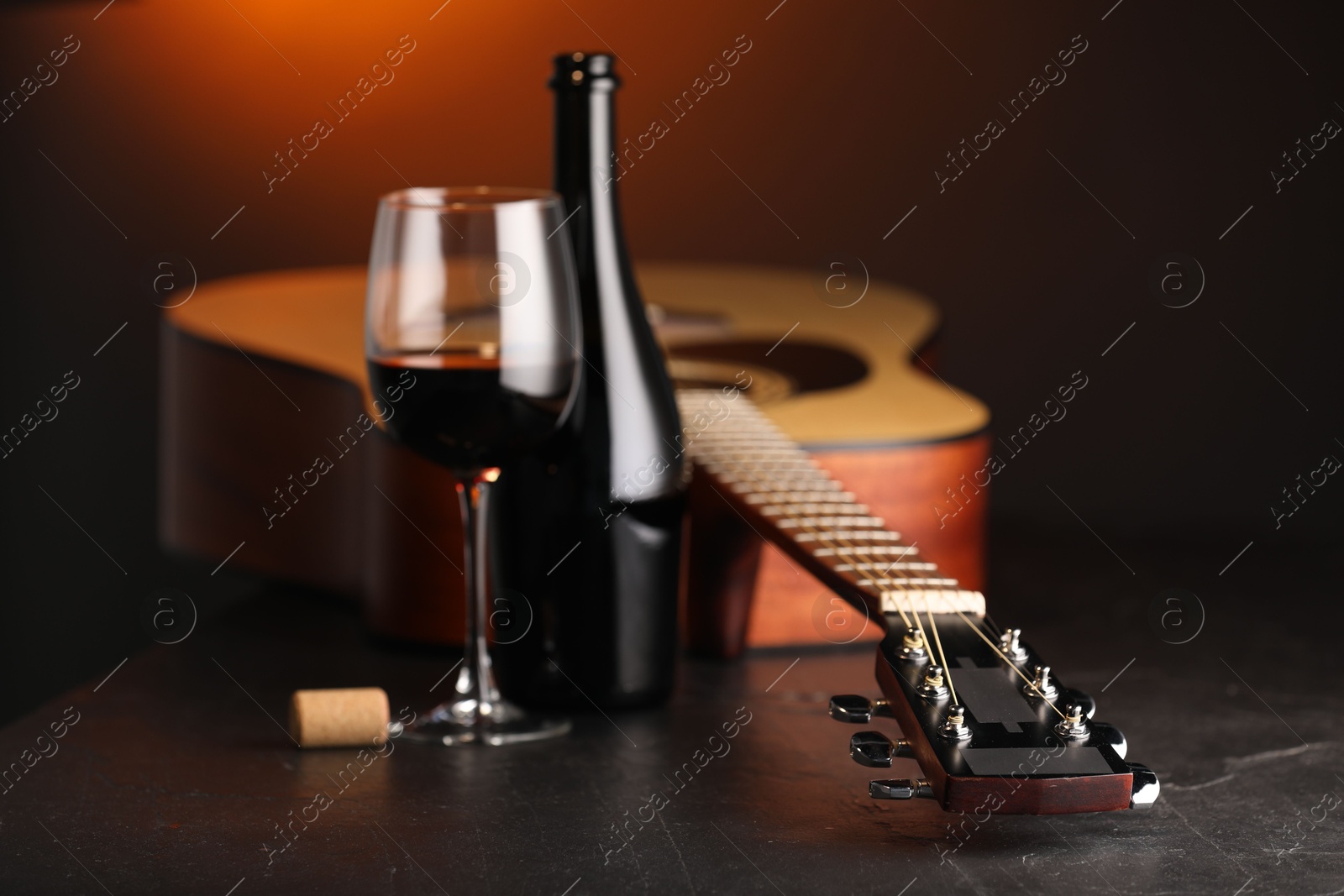 Acoustic guitar and red wine on black table with brown light, closeup Photo of Acoustic guitar and red wine on black table with brown light, closeup