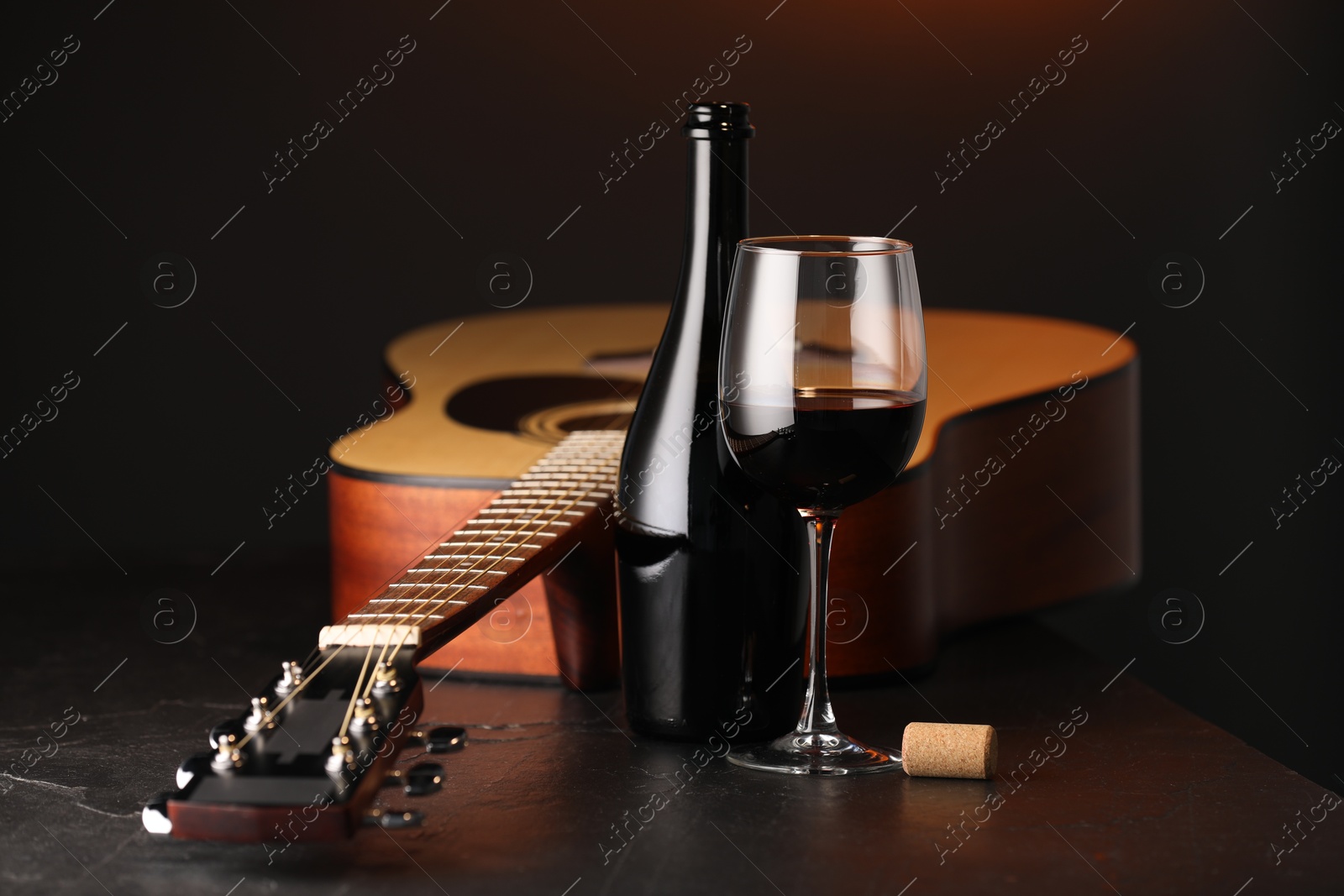 Acoustic guitar and red wine on black table, closeup Photo of Acoustic guitar and red wine on black table, closeup