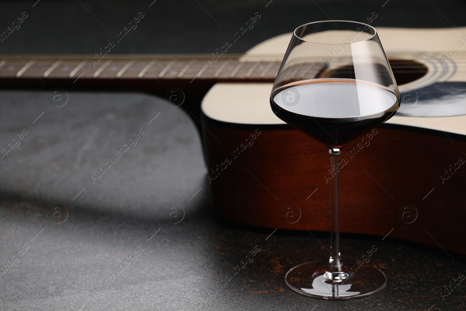 Acoustic guitar and red wine on black table, closeup Photo of Acoustic guitar and red wine on black table, closeup