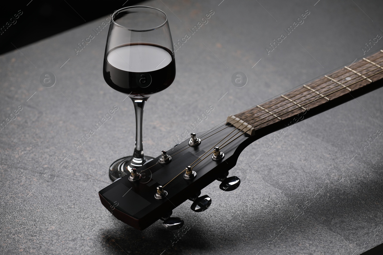 Acoustic guitar and red wine on black table, closeup Photo of Acoustic guitar and red wine on black table, closeup