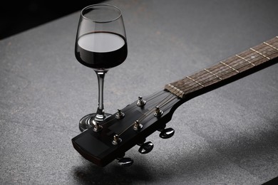 Photo of Acoustic guitar and red wine on black table, closeup