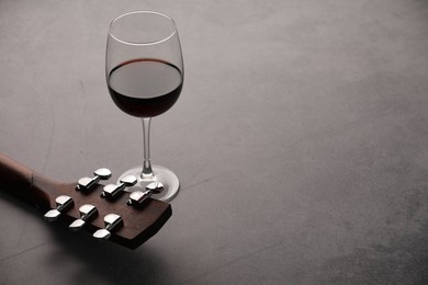 Photo of Acoustic guitar and red wine on grey table, closeup. Space for text