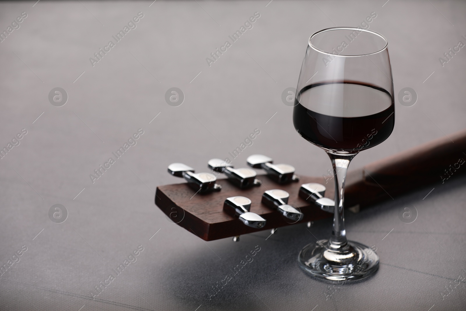 Acoustic guitar and red wine on grey table, closeup. Space for text Photo of Acoustic guitar and red wine on grey table, closeup. Space for text