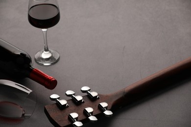 Photo of Acoustic guitar and red wine on grey table, closeup. Space for text