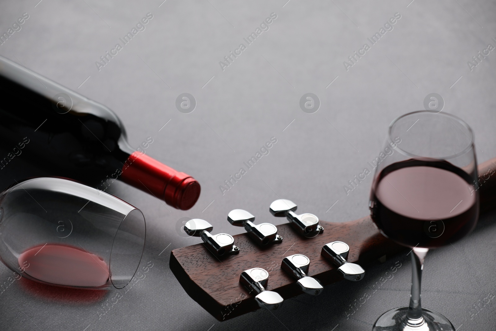 Acoustic guitar and red wine on grey table, closeup. Space for text Photo of Acoustic guitar and red wine on grey table, closeup. Space for text