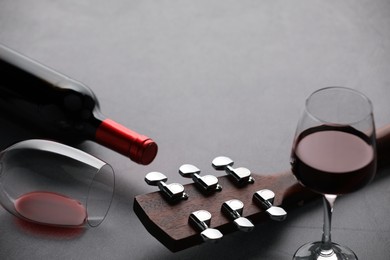 Photo of Acoustic guitar and red wine on grey table, closeup. Space for text