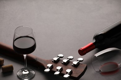 Photo of Acoustic guitar and red wine on grey table, closeup. Space for text