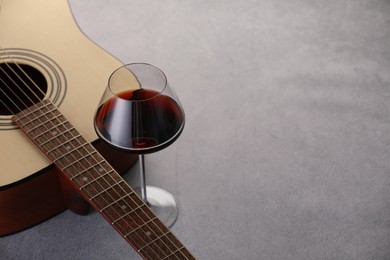 Photo of Acoustic guitar and red wine on grey table, closeup. Space for text