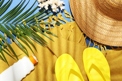 Photo of Beach accessories and palm leaf on blue background, flat lay