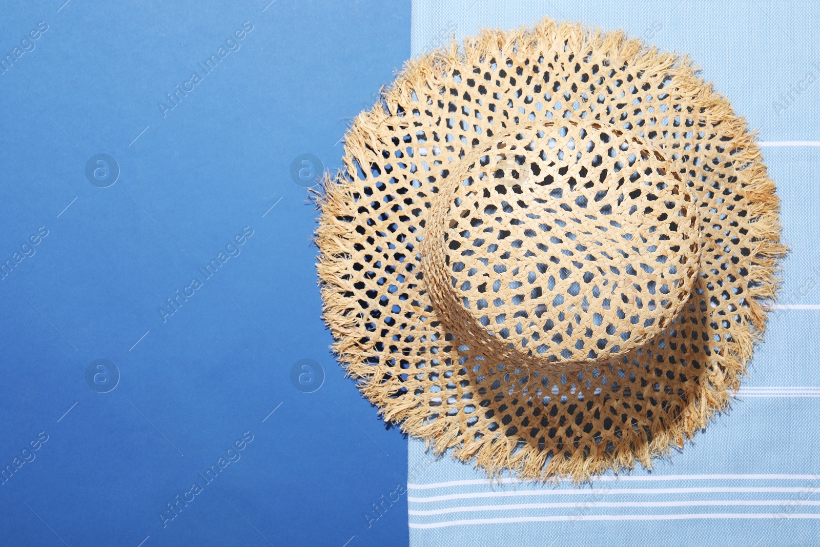 Wicker hat and beach towel on blue background, top view. Space for text Photo of Wicker hat and beach towel on blue background, top view. Space for text