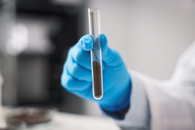 Photo of Scientist with test tube of soil sample in laboratory, closeup