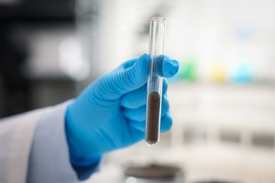 Photo of Scientist with test tube of soil sample in laboratory, closeup