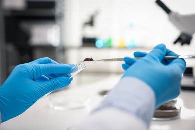 Photo of Scientist taking soil sample for research at table in laboratory, closeup
