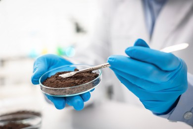 Photo of Scientist taking soil sample for research at table in laboratory, closeup