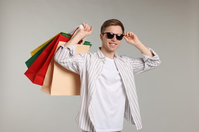 Photo of Cheerful man with shopping bags on light grey background