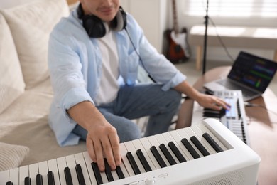 Photo of Man working with digital piano and MIDI keyboard in home studio, selective focus