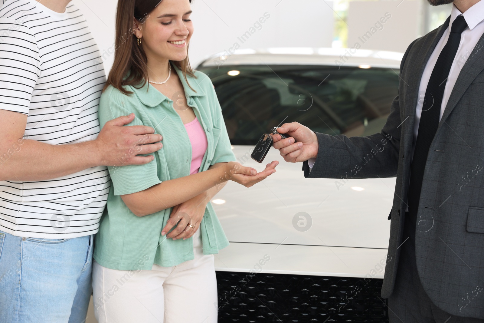Salesman giving car key to family in salon, closeup Photo of Salesman giving car key to family in salon, closeup