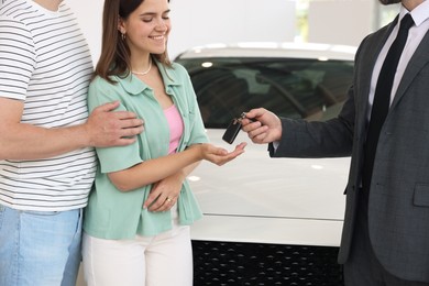 Photo of Salesman giving car key to family in salon, closeup