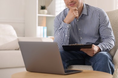 Photo of Psychologist with clipboard during online session by laptop in office, closeup